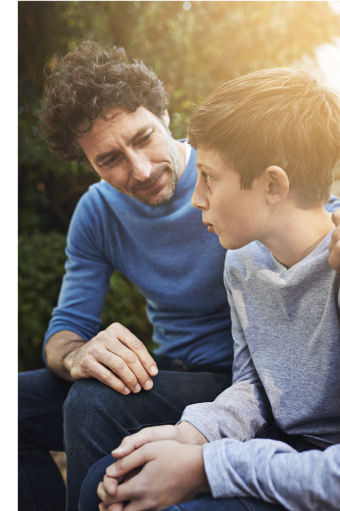 Dad leaned forward with his arm around teenage son. 